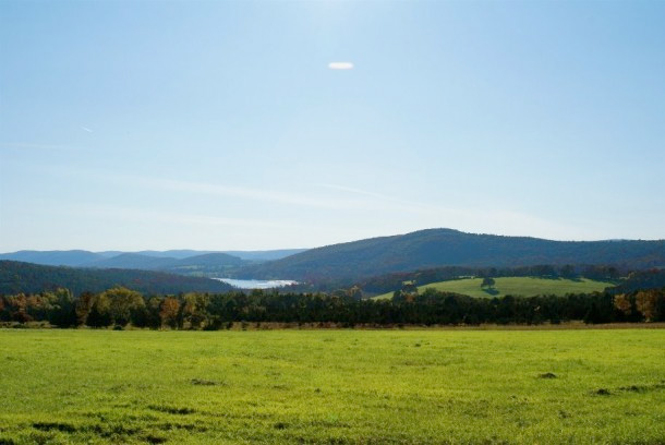 A peaceful green field with distant rolling hills under a clear sky.