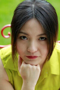 Close-up of a woman resting her chin on her hand, looking thoughtfully.