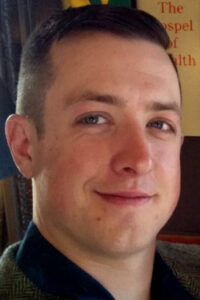 Close-up portrait of a smiling man with short hair.